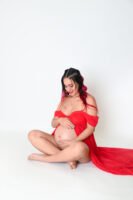 Retrato de maternidad con vestido rojo en estudio