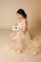 Retrato de maternidad con vestido de tul sobre fondo beige