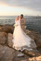 Retrato de novios junto al mar con el velo extendido