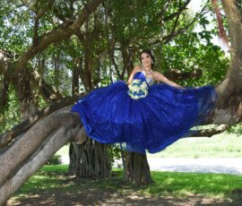 Quinceañera con vestido azul entre árboles