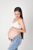 Retrato de maternidad con pantalones de mezclilla en estudio