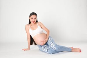 Retrato de maternidad con pantalones de mezclilla en estudio