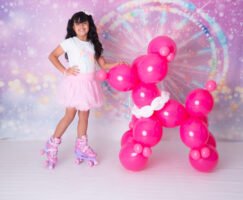 Retrato infantil junto a una figura de globos rosas