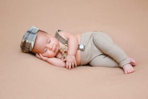 Bebé recién nacido dormido con diadema y ropa clara