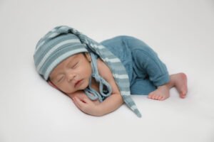 Bebé recién nacido dormido con gorro y ropa azul