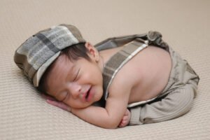 Bebé recién nacido dormido con gorra y tirantes