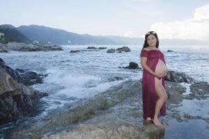 Retrato de maternidad con vestido morado junto al mar