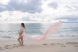 Sesión de embarazo junto al mar con vestido rosa