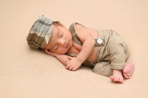 Bebé recién nacido dormido con gorro y ropa beige