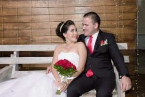 Novios sentados juntos con un ramo de rosas rojas