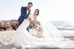 Retrato de novios junto al mar con el velo extendido