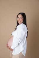 Retrato de maternidad con ropa blanca sobre fondo beige