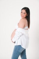 Retrato de maternidad con ropa blanca sobre fondo beige
