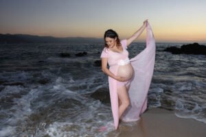 Sesión de embarazo junto al mar con vestido rosa