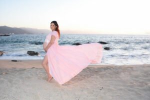 Sesión de embarazo junto al mar con vestido rosa