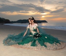 Quinceañera con vestido verde frente al mar al atardecer