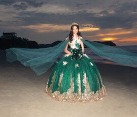 Quinceañera con vestido verde frente al mar al atardecer