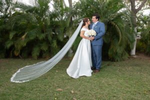 Novios abrazados con el velo extendido en un jardín
