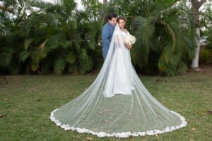 Novios abrazados con el velo extendido en un jardín
