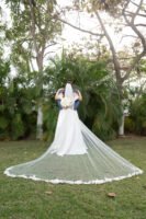 Novios abrazados con el velo extendido en un jardín