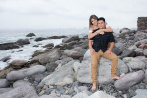 Pareja sentada sobre rocas junto al mar