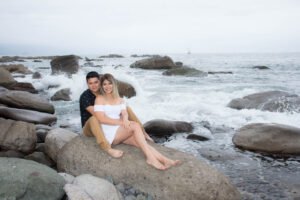 Pareja sentada sobre rocas junto al mar