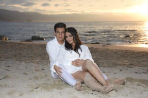 Pareja sentada en la playa al atardecer