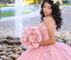 Quinceañera con vestido rosa y ramo en un jardín