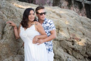 Pareja abrazada junto a las rocas de la playa