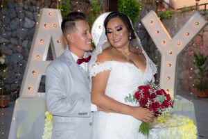 Novios con un ramo junto a letras decorativas
