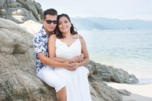Pareja abrazada junto a las rocas de la playa