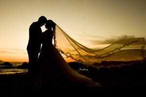 Silueta de novios con el velo al atardecer
